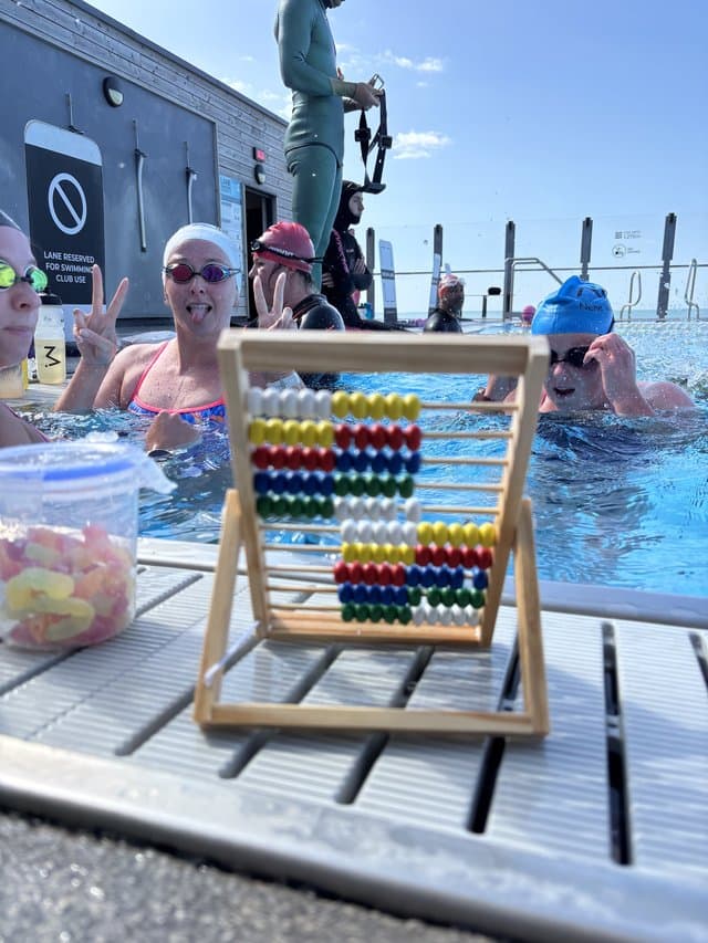 Swimmers resting in the lane between reps, with a tub of sweets on the poolside