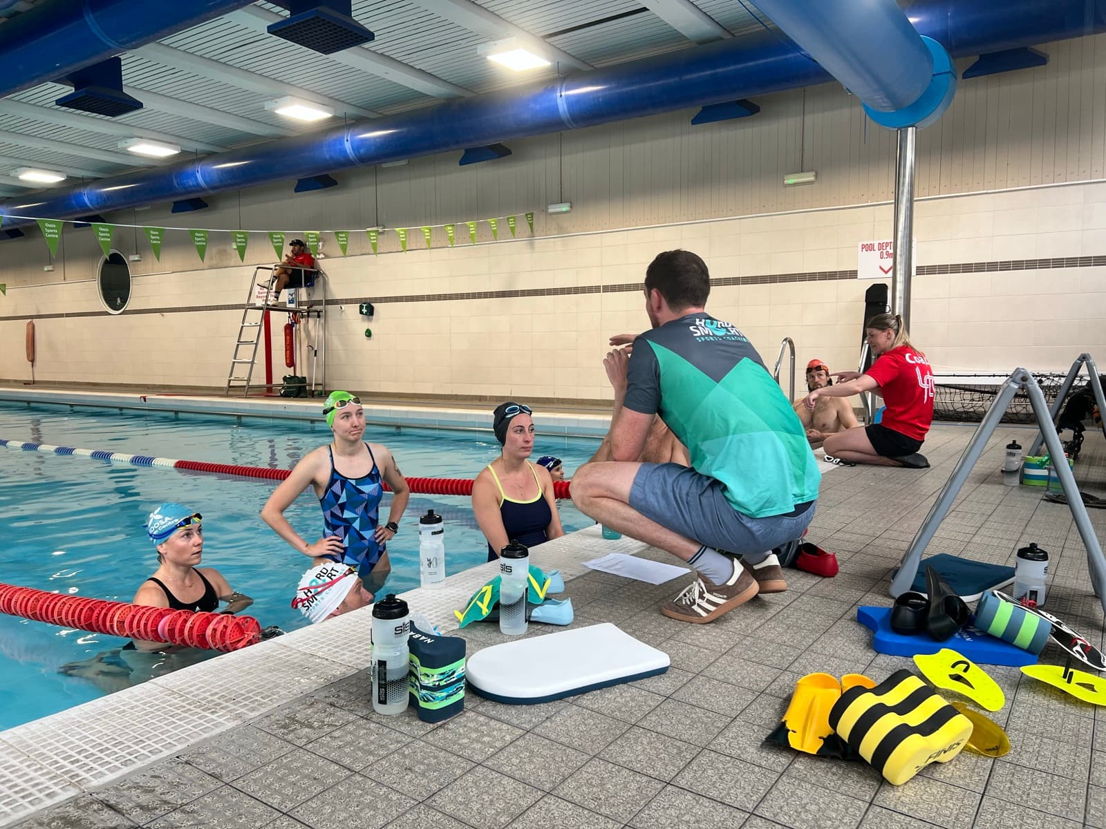 A coach talking through technique with swimmers poolside