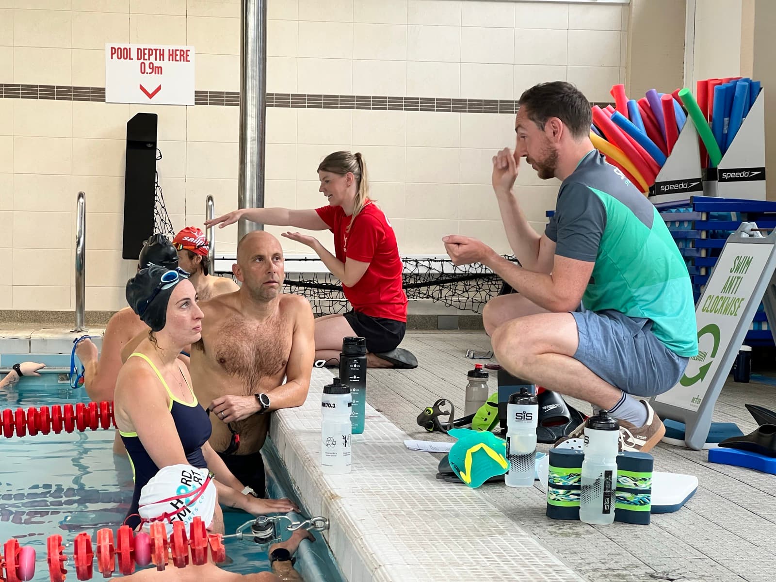 Coaches demonstrating a stroke to swimmers in the water
